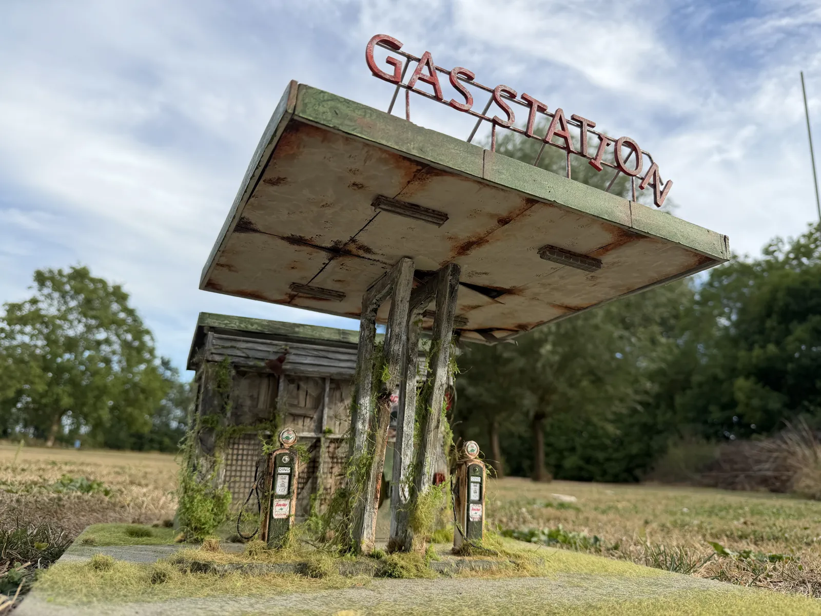 The rusted canopy with the Gas Station sign, photographed outside under a blue sky
